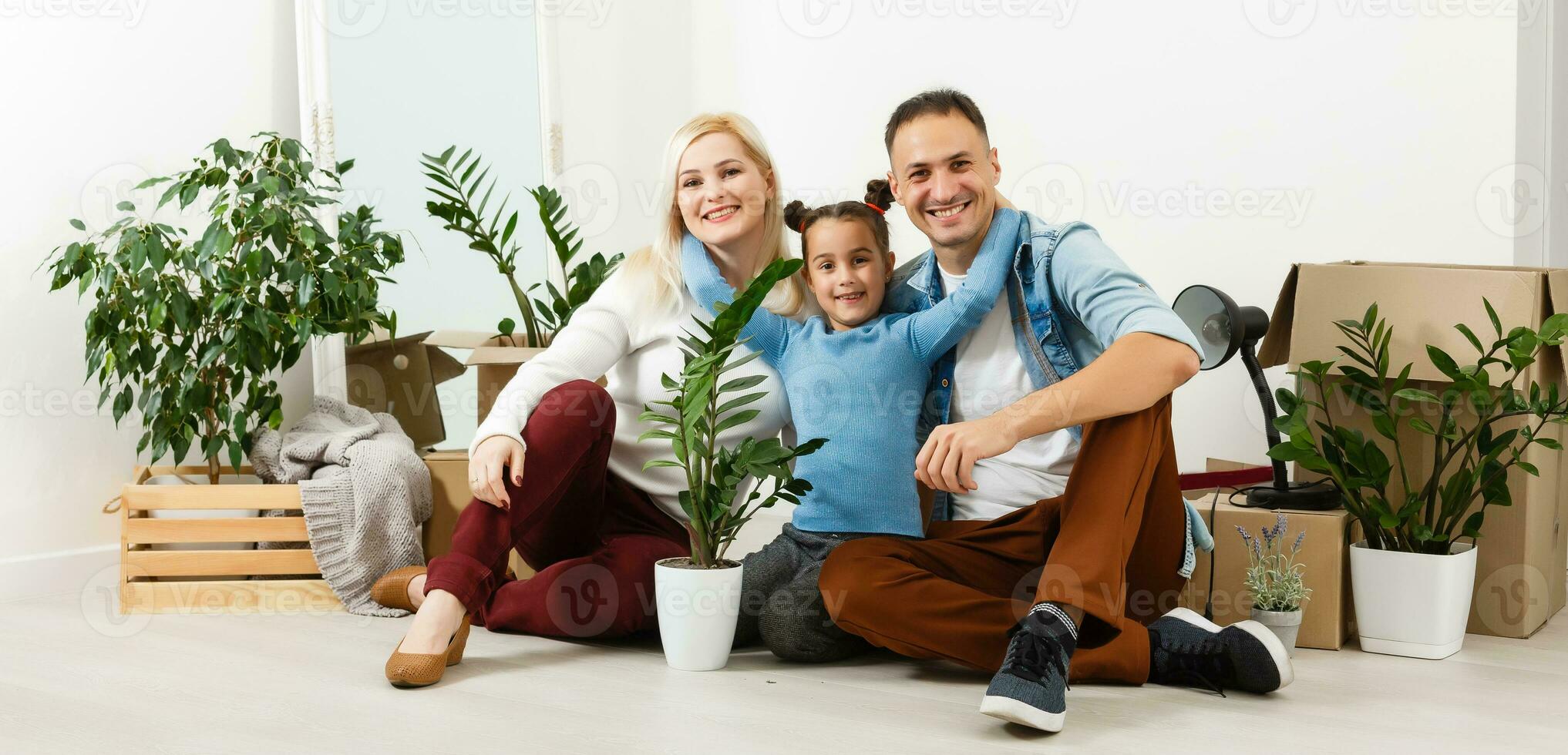 Happy family sitting on wooden floor. Father, mother and child having fun together. Moving house day, new home and design interior concept photo