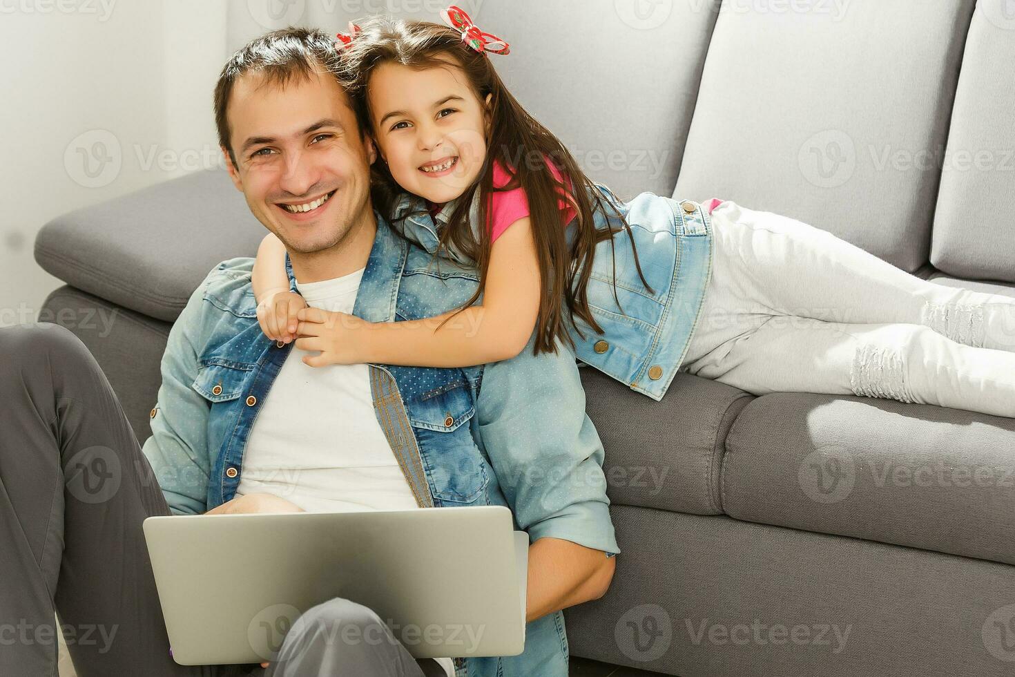 Bearded man and little girl at home family time sitting on floor on carpet browsing laptop together smiling joyful photo