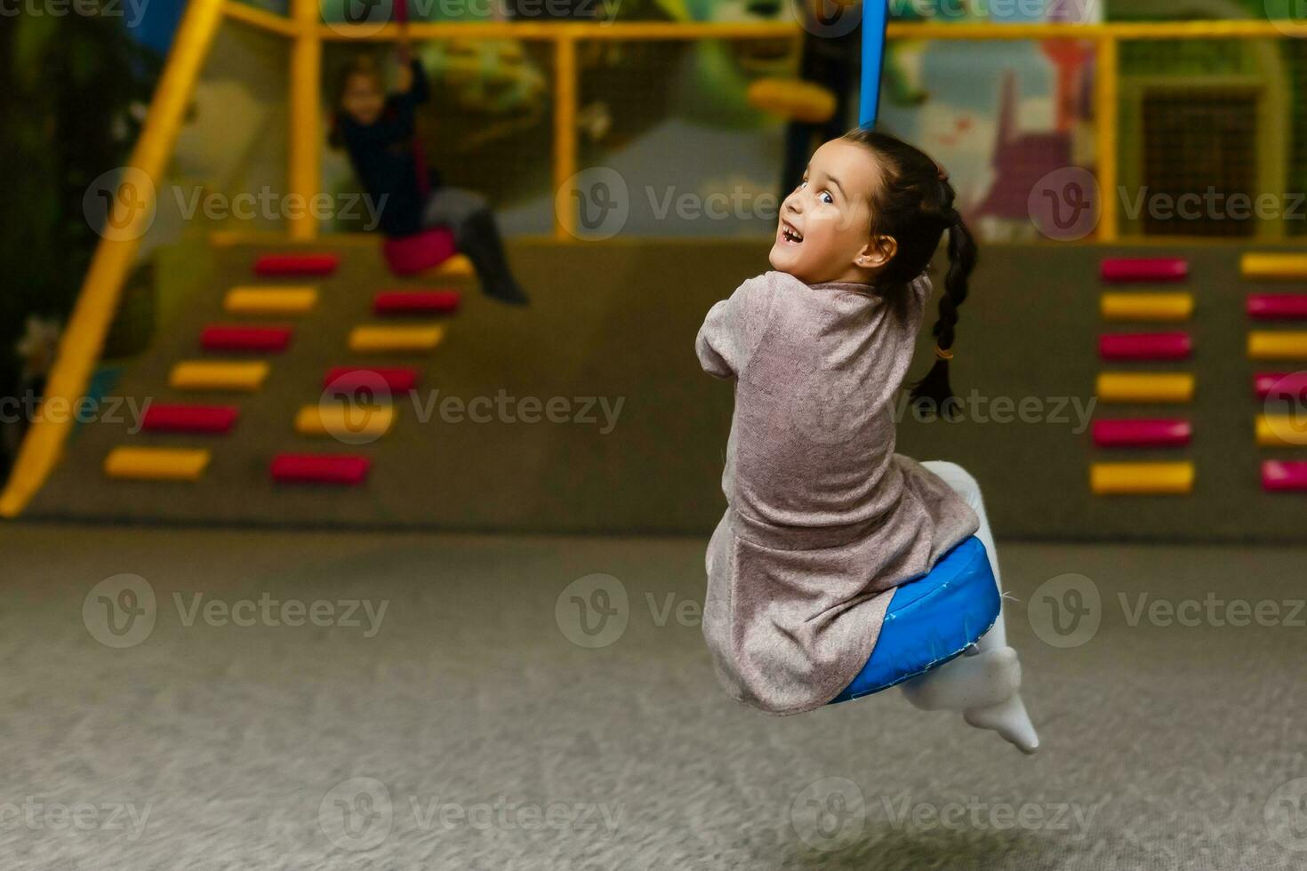 Cute little girl is playing on the playground. The girl is riding on a swing. photo