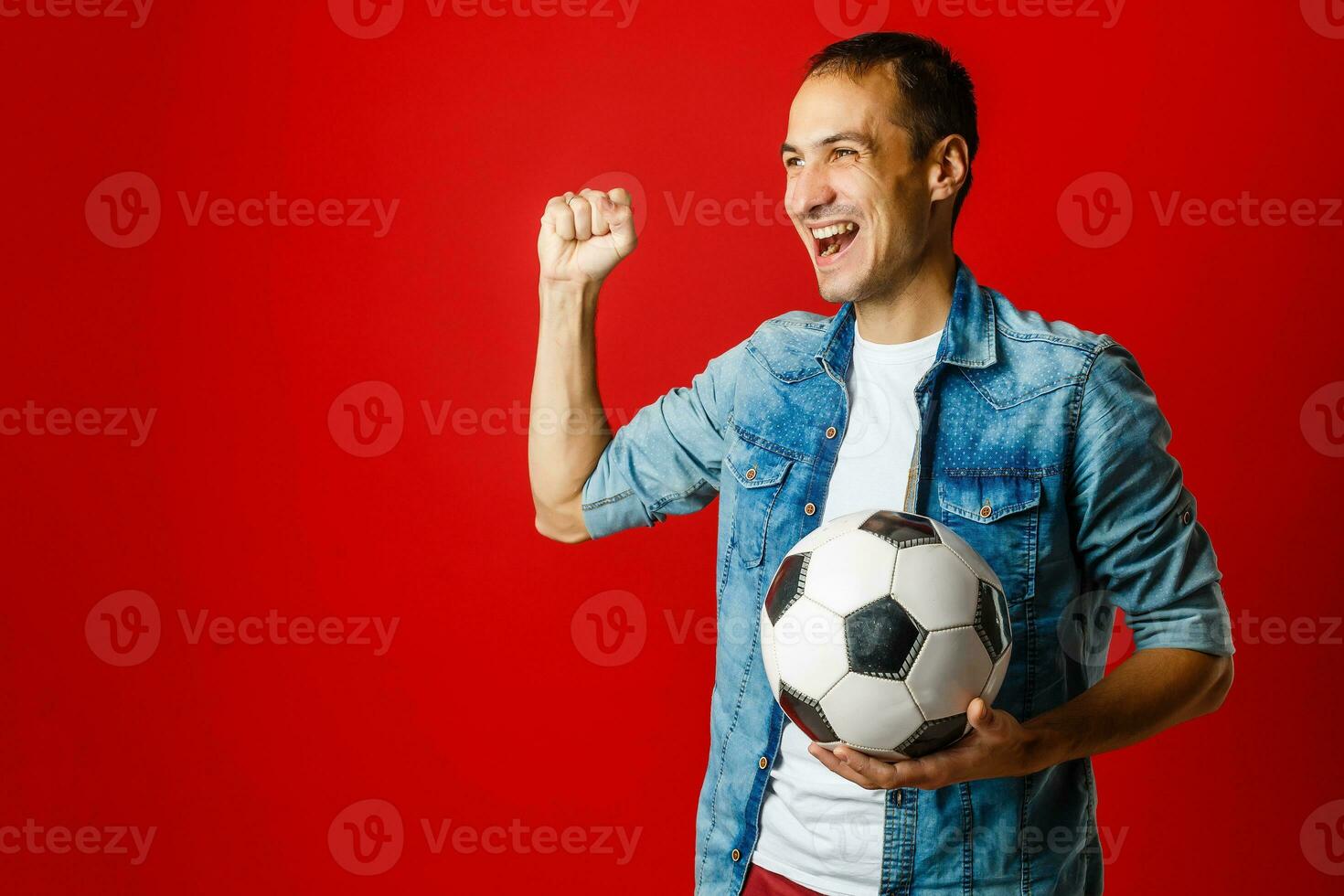 Handsome man holding a soccer ball over red backgound photo