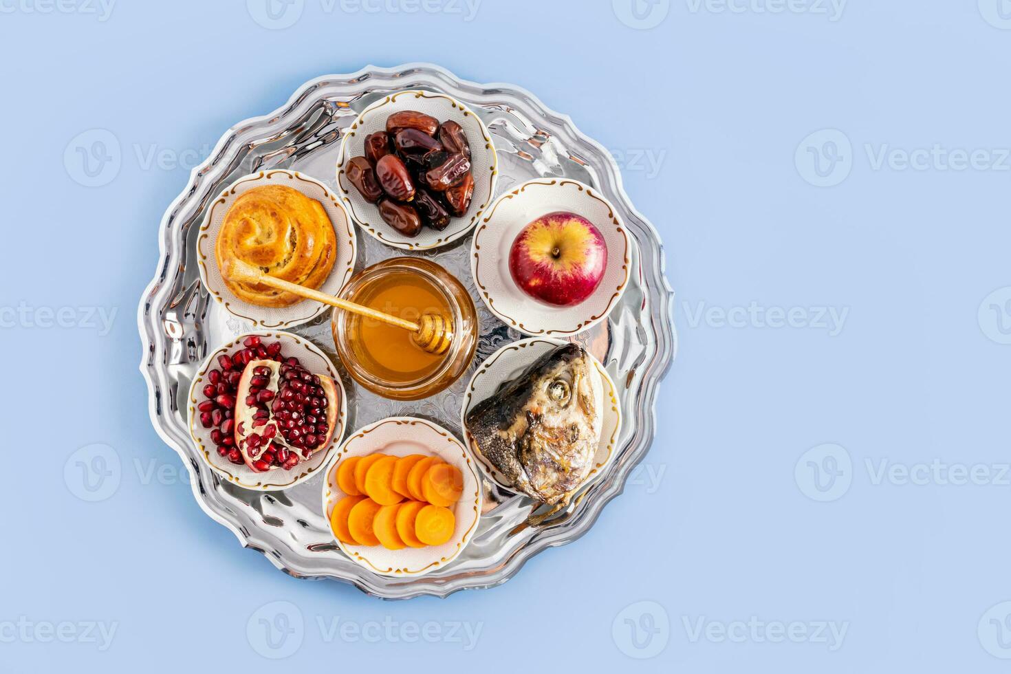 A silver plate with traditional treats for the Jewish New Year. The concept of the holiday of Rosh Hashanah. Top view. Blue background. copy space photo