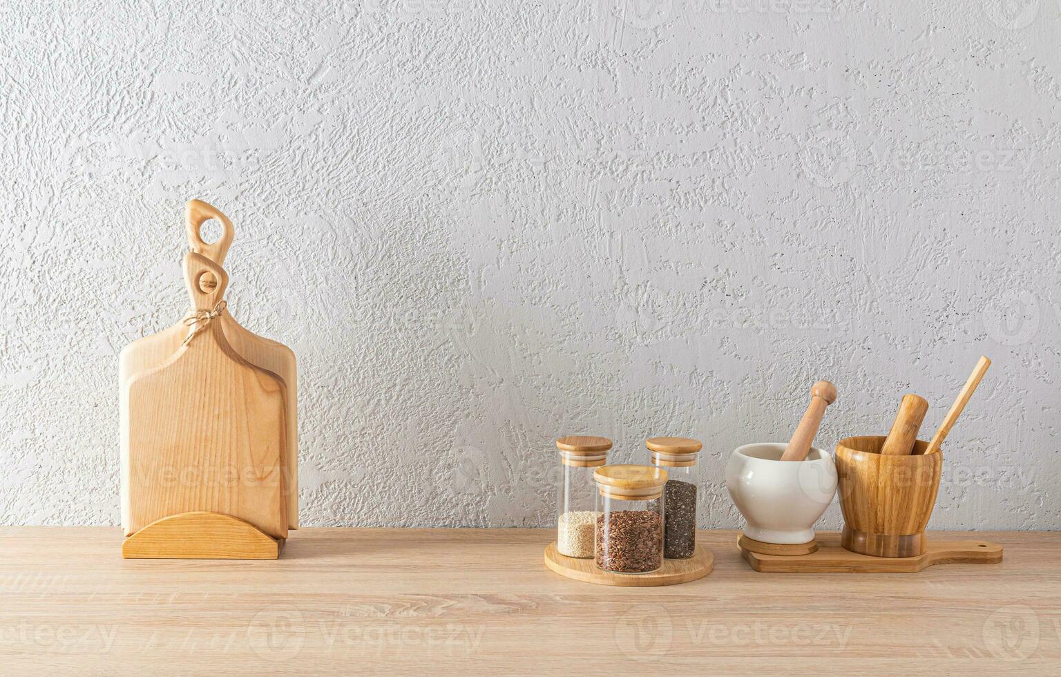 A set of glass spice jars, two mortars with a pestle, cutting wooden boards on the kitchen countertop. minimalism in the interior of a modern kitchen. photo