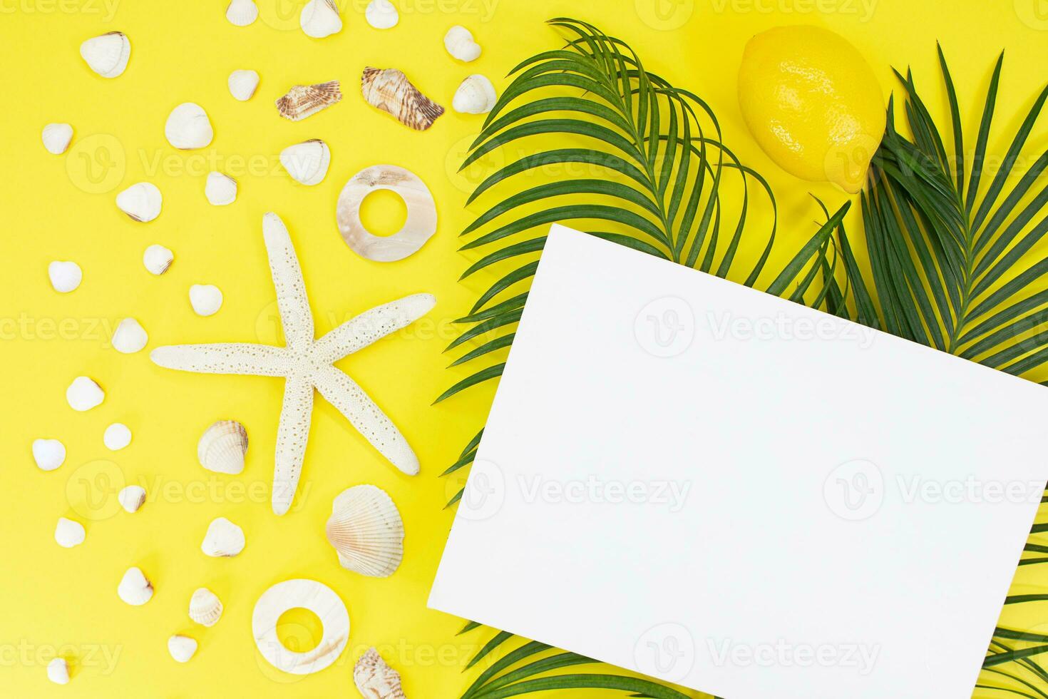 White starfish, shells with palm leaves and paper for text on side on yellow background. Flat lay. Travel, vacation, summer. Copy space photo