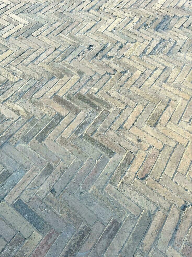 Old tiles on the ground. Zigzag tiling. Abstract background with old stones. Light colors. Vertical composition. Textured gray background. Mosaic floor tiles in rectangles in shades of gray and white photo