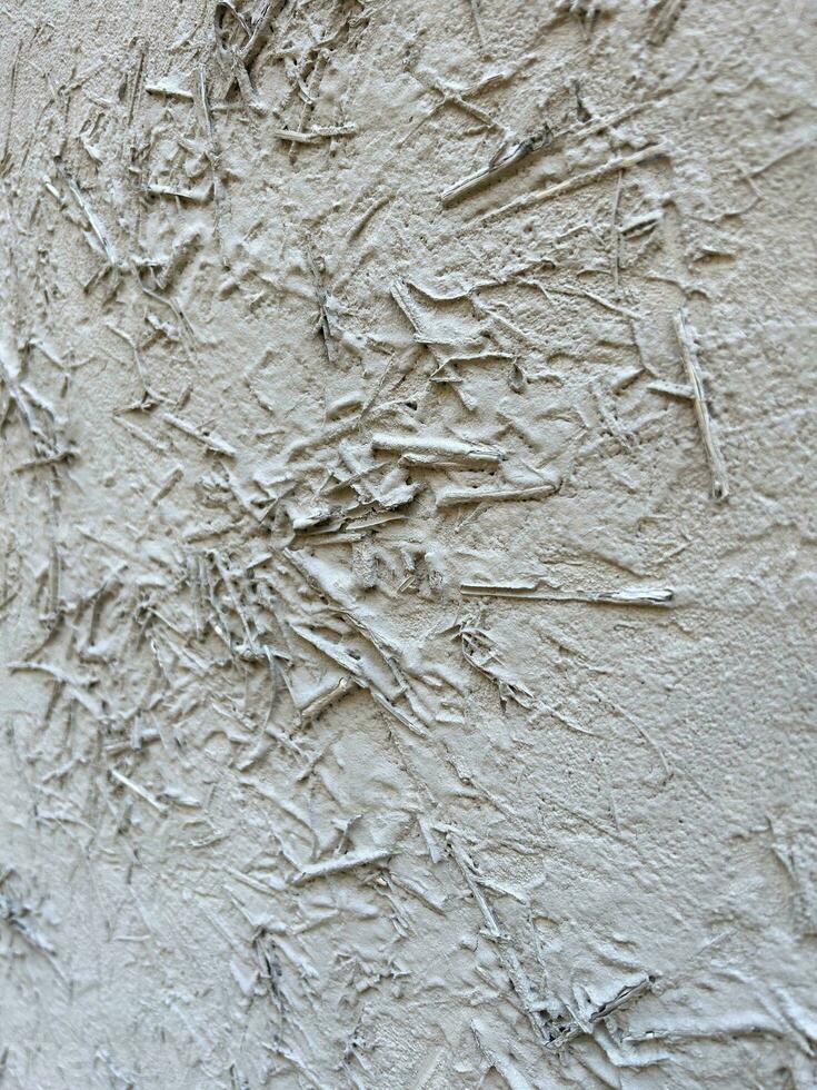 Wall painted with white paint. White wall is painted with hay and rice straw. Abstract background with old white plaster. Grey color. Vertical composition. Textured gray background. photo