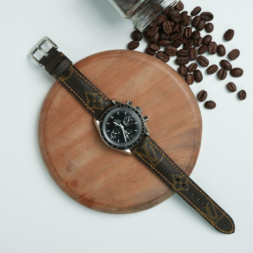 Surabaya, IDN, 2023 - Photography of luxury watch with black dial and leather strap with fashion theme, against wood and coffee bean background photo