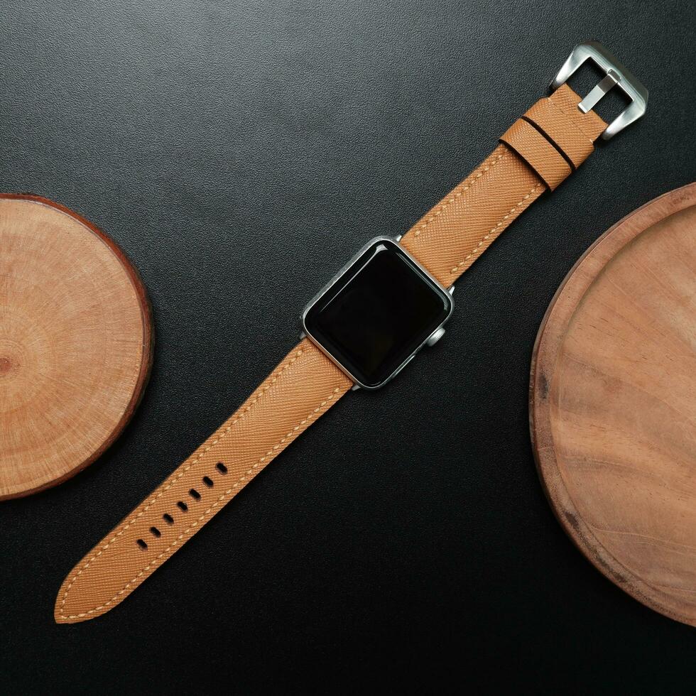 Surabaya, IDN, 2023 - Photography of a smartwatch with a light brown strap, against a dark background and wood cutout photo