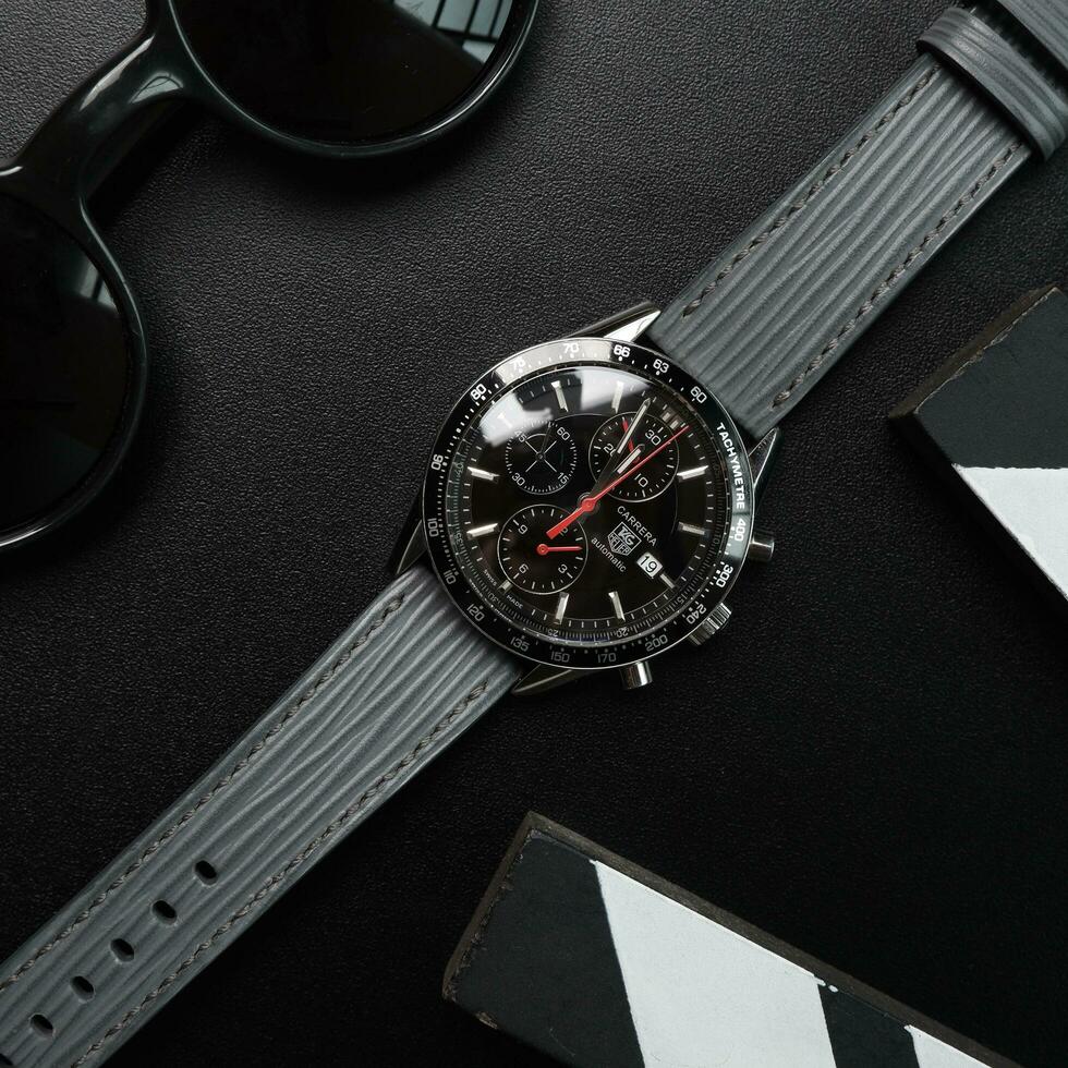 Surabaya, IDN, 2023 - Photography of a sporty style luxury watch with a gray strap, against a dark Hollywood themed background photo