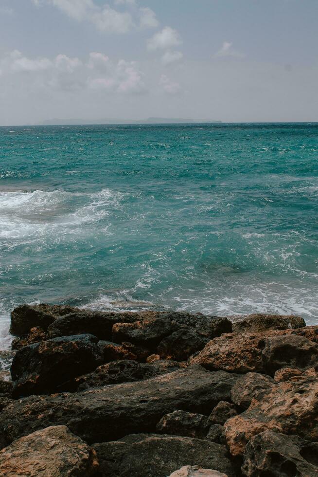 Rocky beach in Mallorca, in summer at high tide with the waves hitting and breaking on the coast. photo