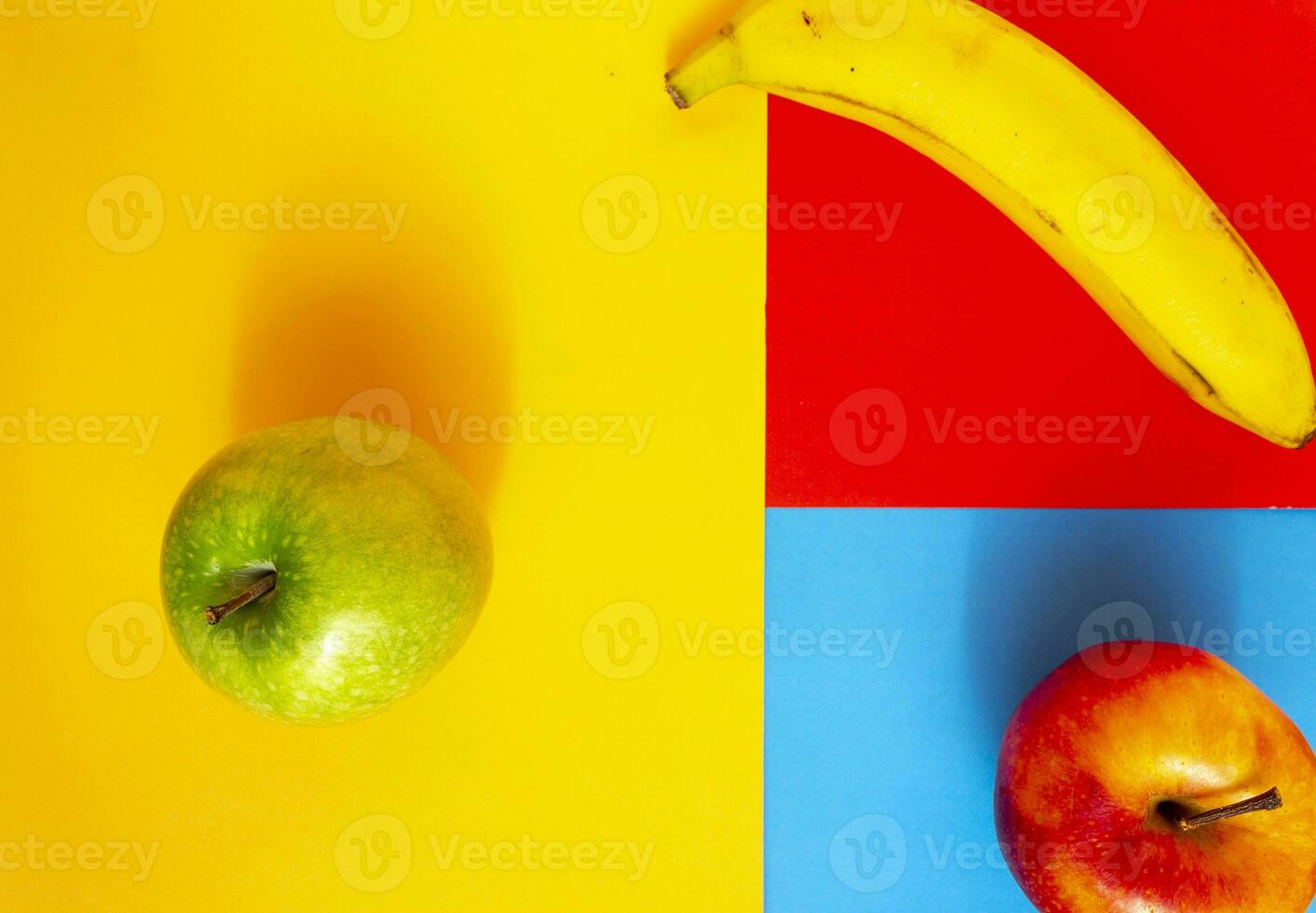 Red apple, green apple and banana on three colors background. Abstract background of fruits with creative design thinking. photo