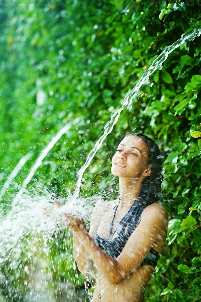 a woman in a bikini is splashing water on her head photo