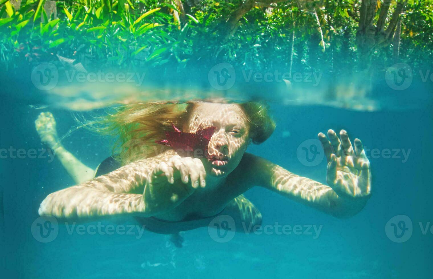 a woman swimming underwater in the ocean photo