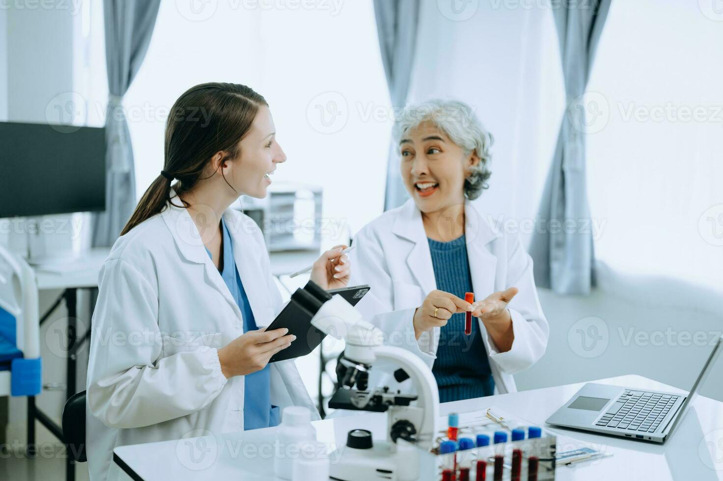Two scientist or medical technician working, having a medical discuss meeting with an Asian senior female scientist supervisor in the laboratory with online reading, test samples and innovation photo