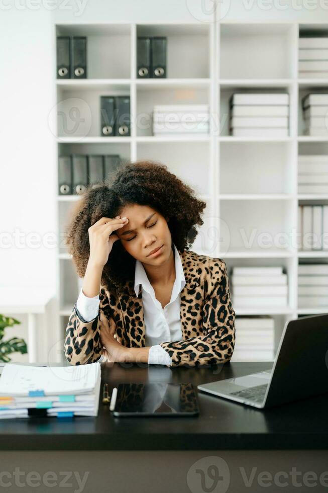 African Woman who is tired and overthinking from working with tablet and laptop at office. photo