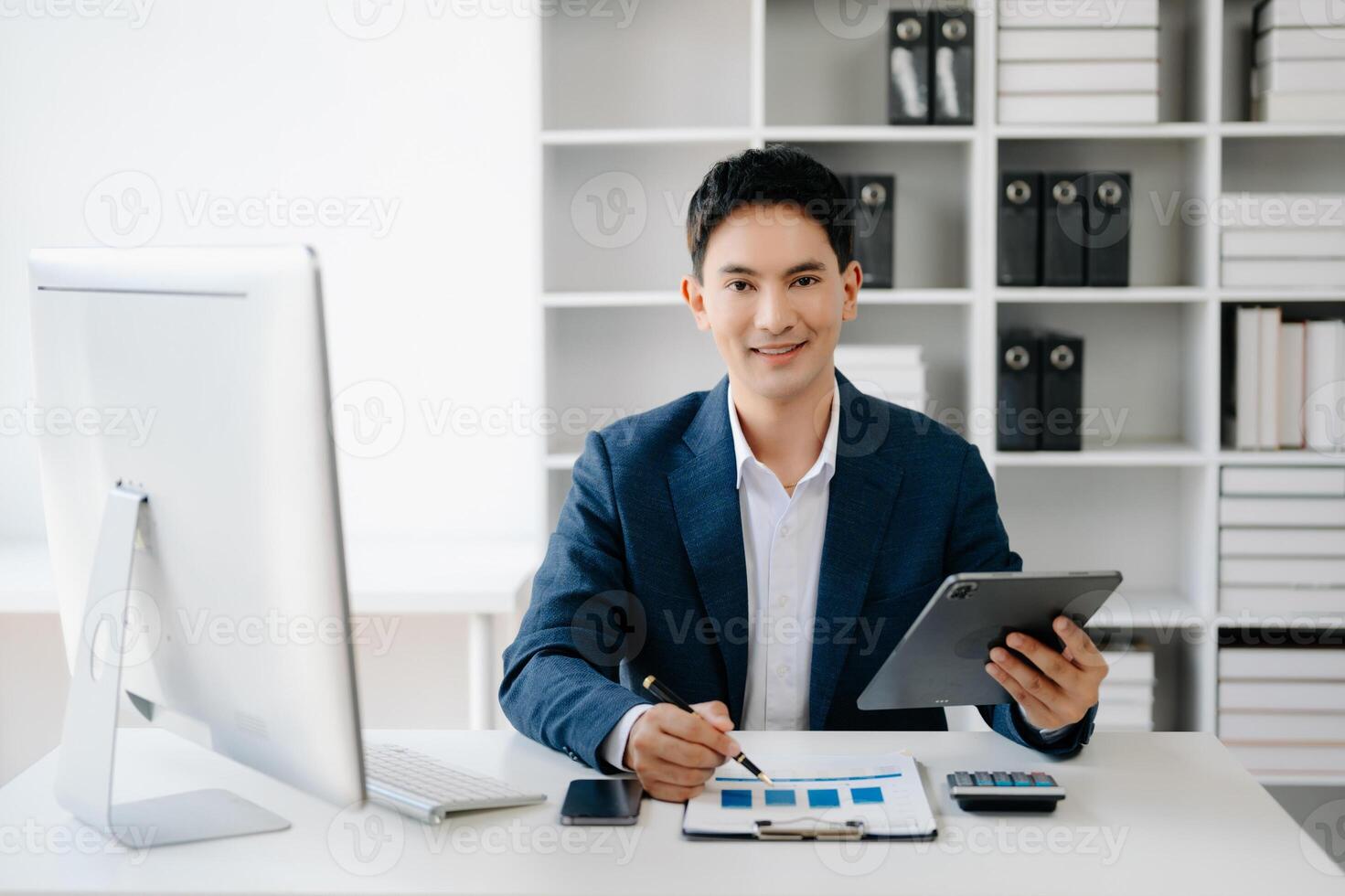 Business man using tablet and laptop for doing math finance on an office desk, tax, report, accounting, statistics, and analytical research concept in office photo