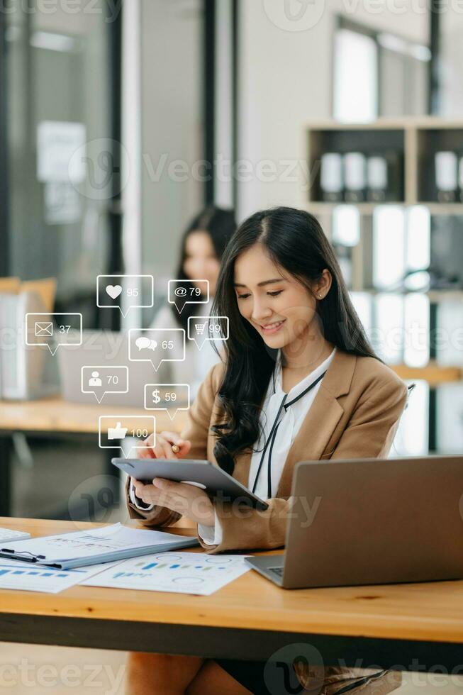 Asian woman typing smartphone, keyboard  with laptop computer of Social media and marketing virtual icons screen concept. photo
