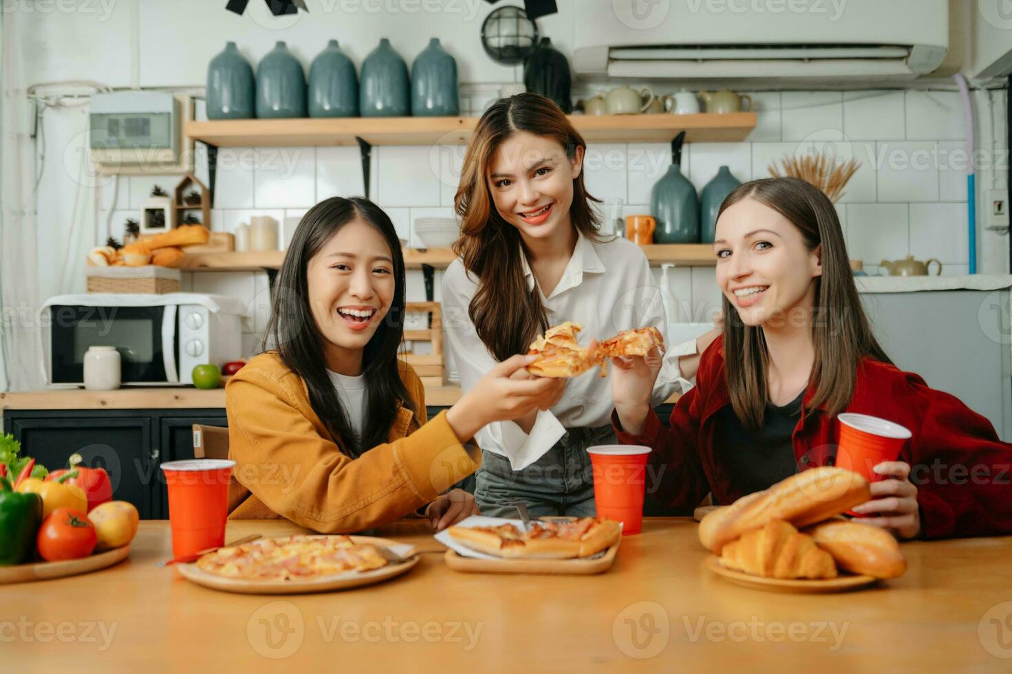 grupo de amigos haciendo divertido a hogar fiesta.ellos sentado en escritorio en vivo habitación y comiendo Pizza. contento foto