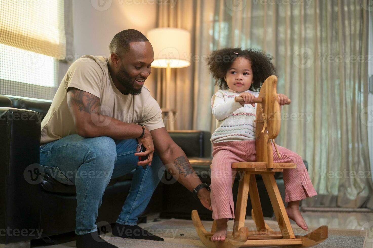 Happy African American man playing with his daughter in living room at home photo