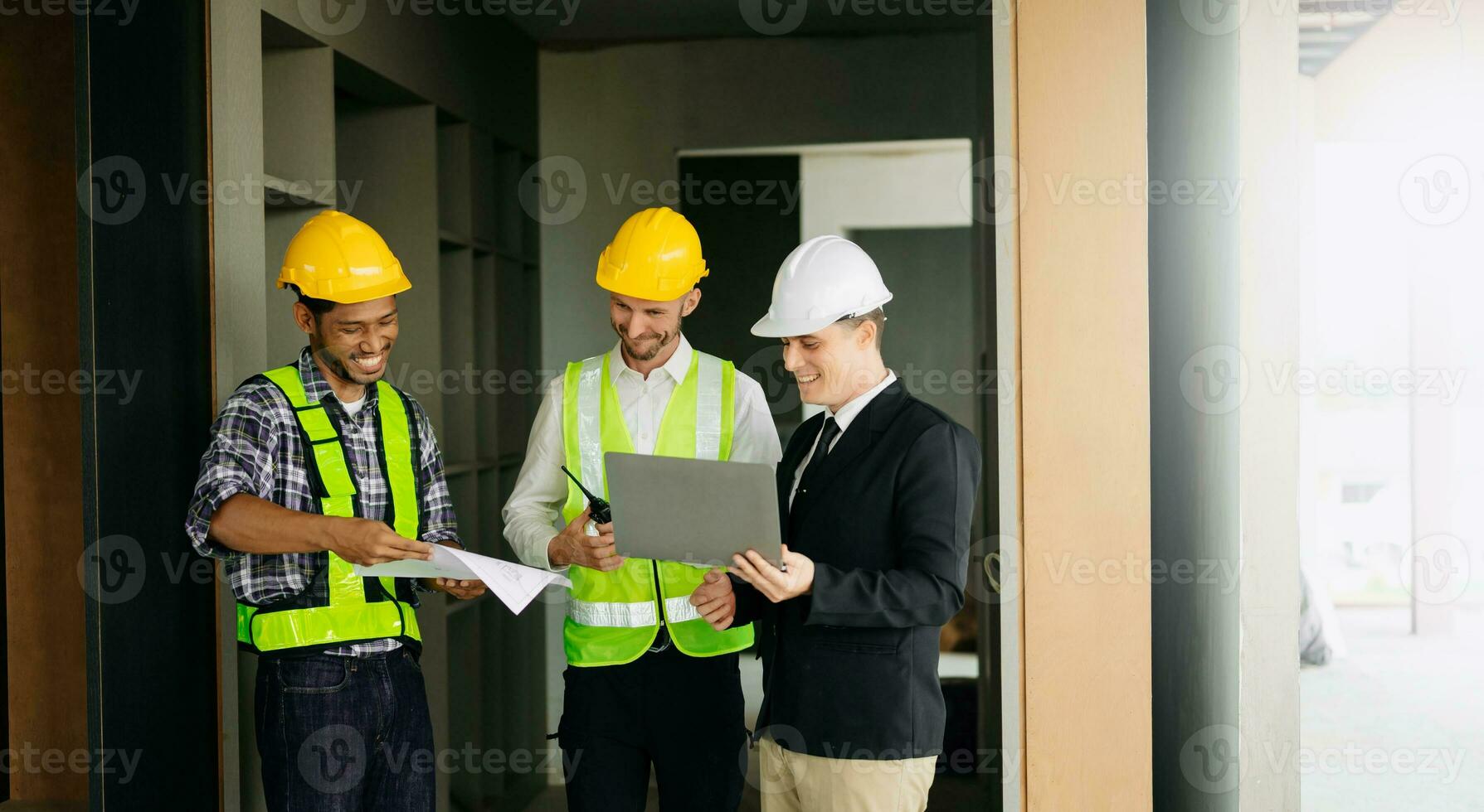 Contractor and architect looking at plan, tablet, laptop and talking about working on big project. Building in construction process photo