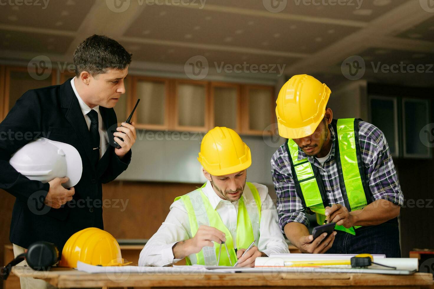 Contractor and architect looking at plan, tablet, laptop and talking about working on big project. Building in construction process photo
