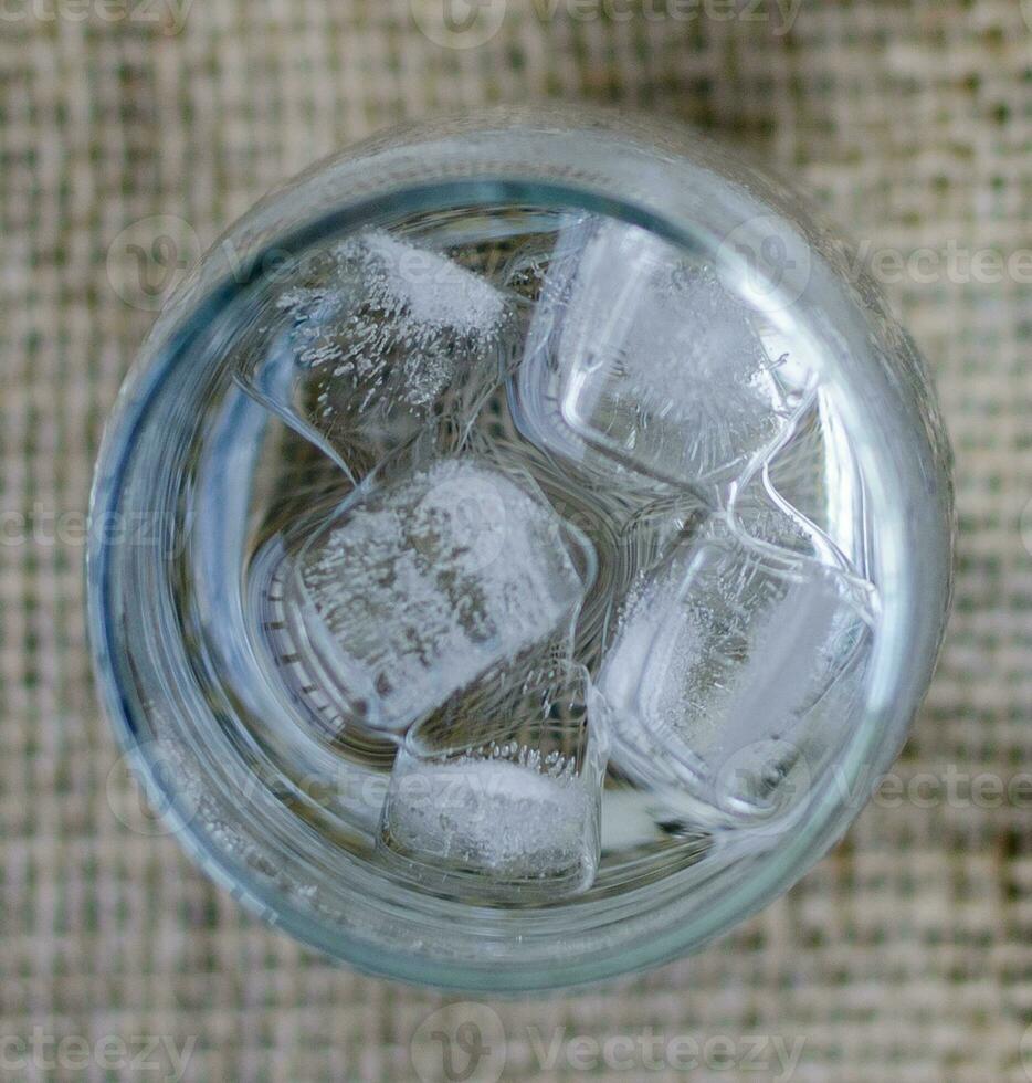 Closeup top view Cold drinking water with ice in a clean glass, drink healthy and cool down. photo