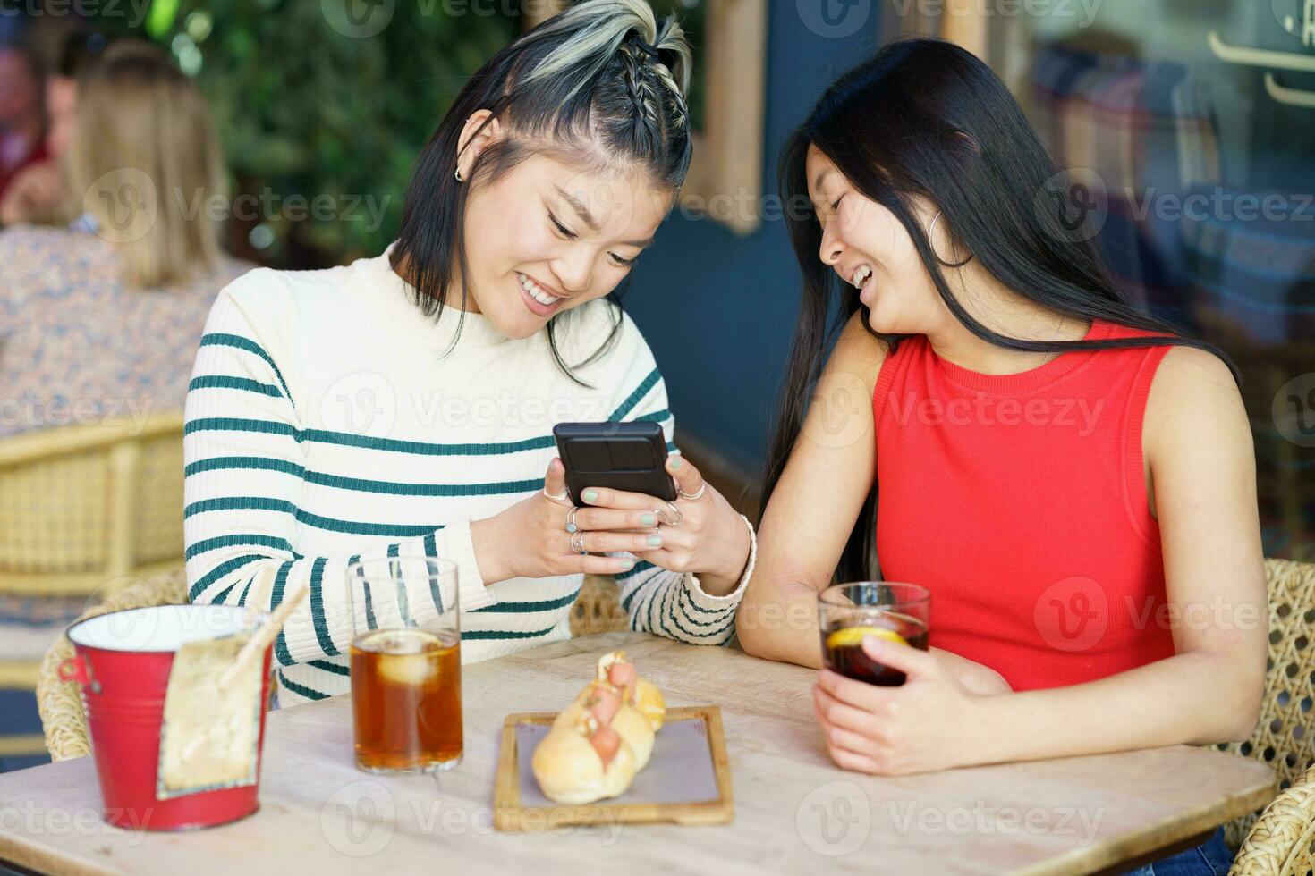 Cheerful Asian women taking picture of yummy food in cafe photo