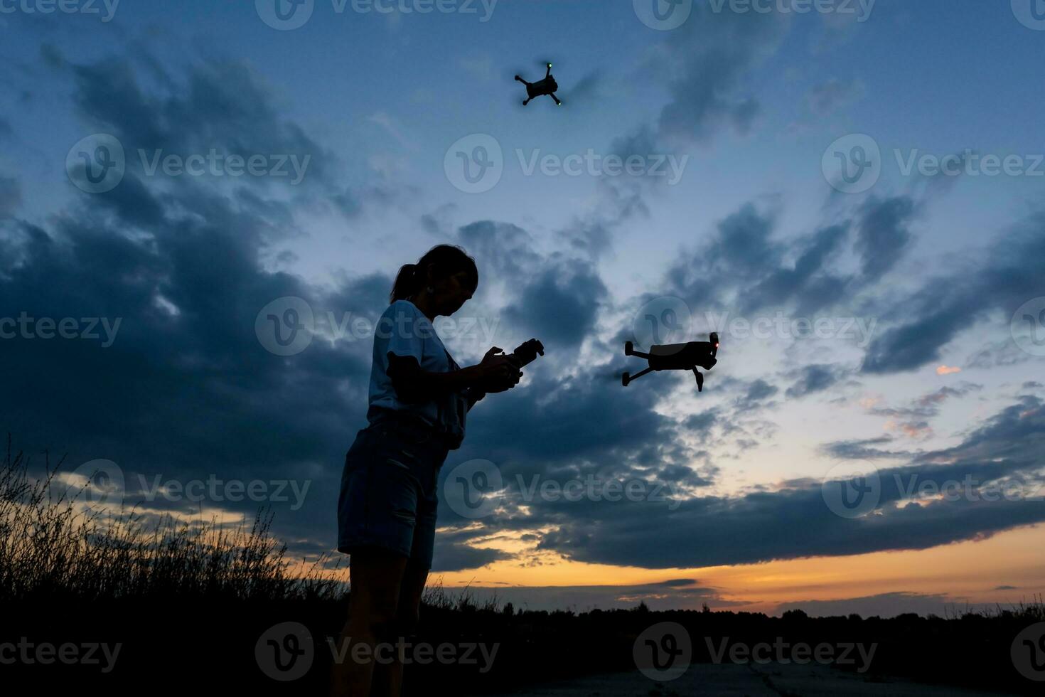 silhouette of woman controlling drone on sunset background photo