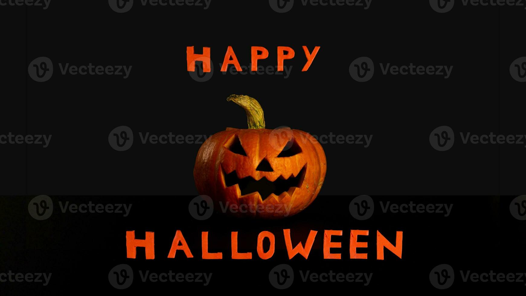 Splash screen Happy Halloween pumpkin lantern with evil grin black background photo