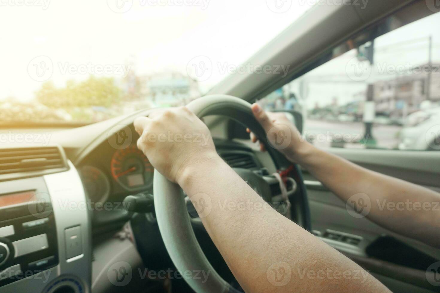 Blurred close up of hands on steering wheel in sunny day traffic jam, driving car on highway. photo