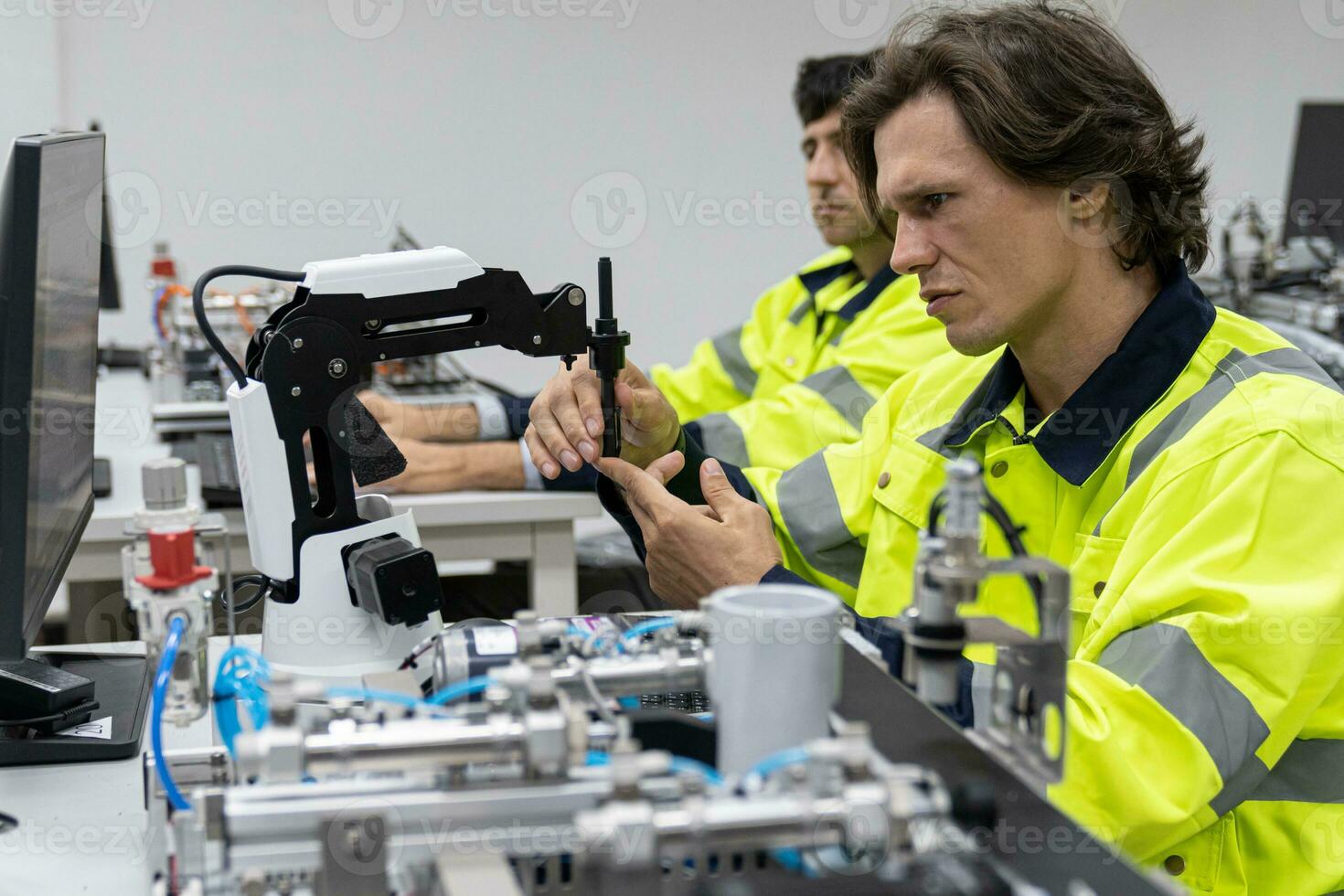 Two male automation machine engineer students studying training Programmable logic controller Technical Industrial Engineer control robotics with monitoring system software, Automation robot arm. photo