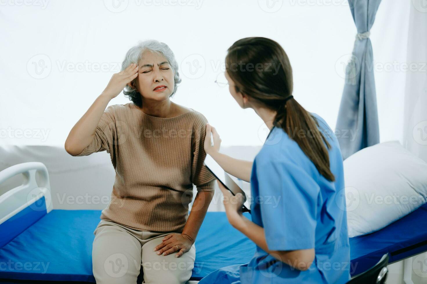 Friendly Female Head Nurse Making Rounds does Checkup on Patient Resting in Bed. She Checks tablet while Man Fully Recovering after Successful Surgery in hospital photo