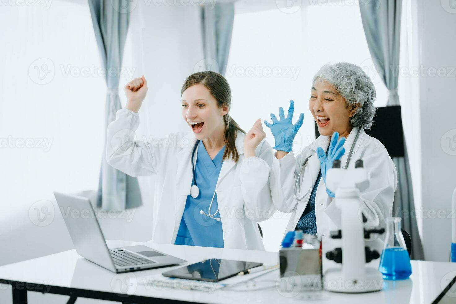 Medical team having a meeting with doctors in white lab coats and surgical scrubs seated at a table discussing a patients working online using computers in the medical industry photo