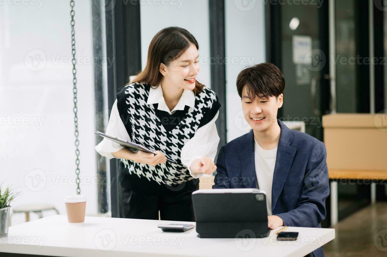 Two Asian business workers talking on the smartphone and using laptop at the modern office. photo