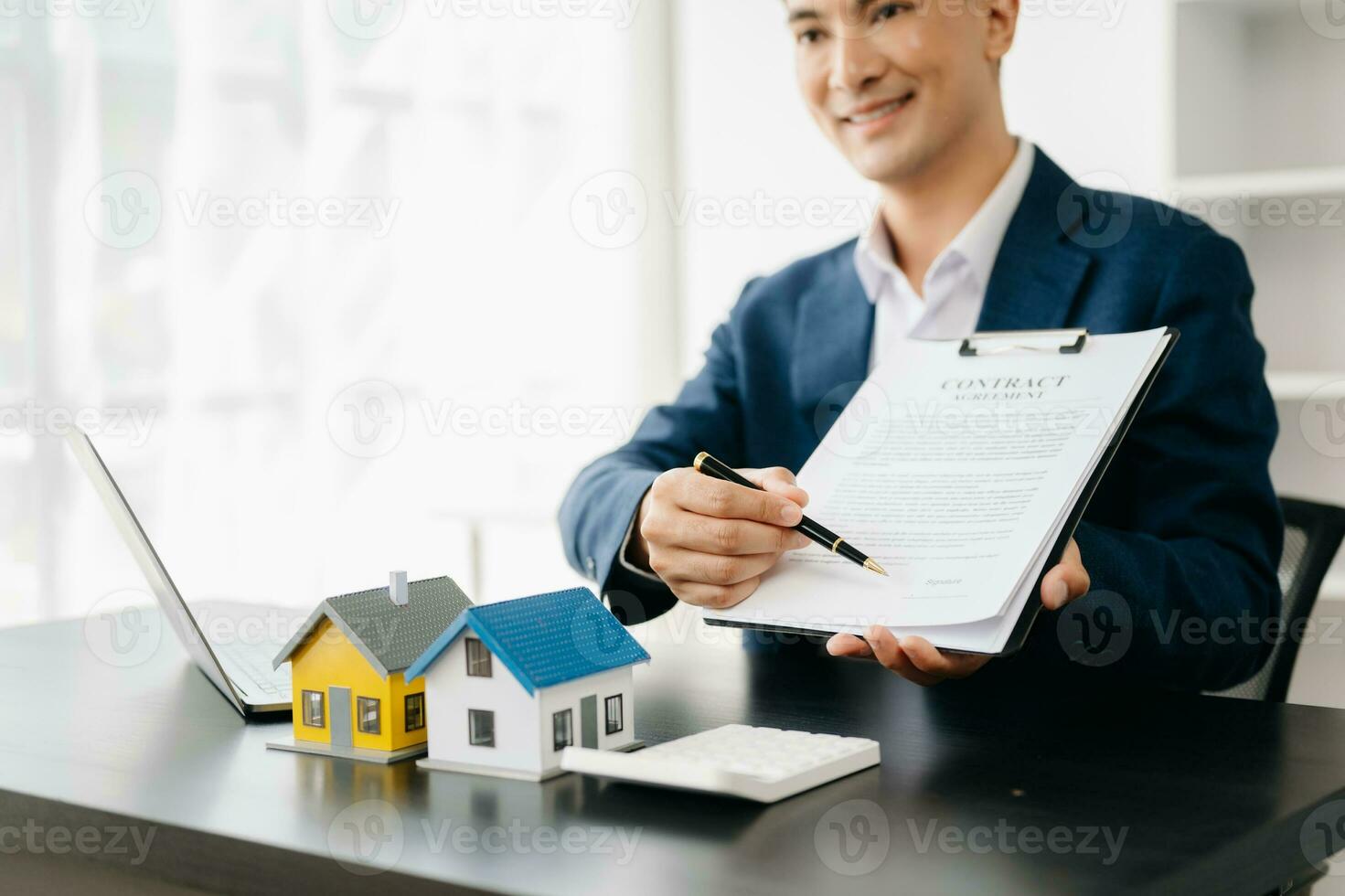 Real estate broker agent presenting and consult to customer to decision making sign insurance form agreement, home model, concerning mortgage loan offer in office photo