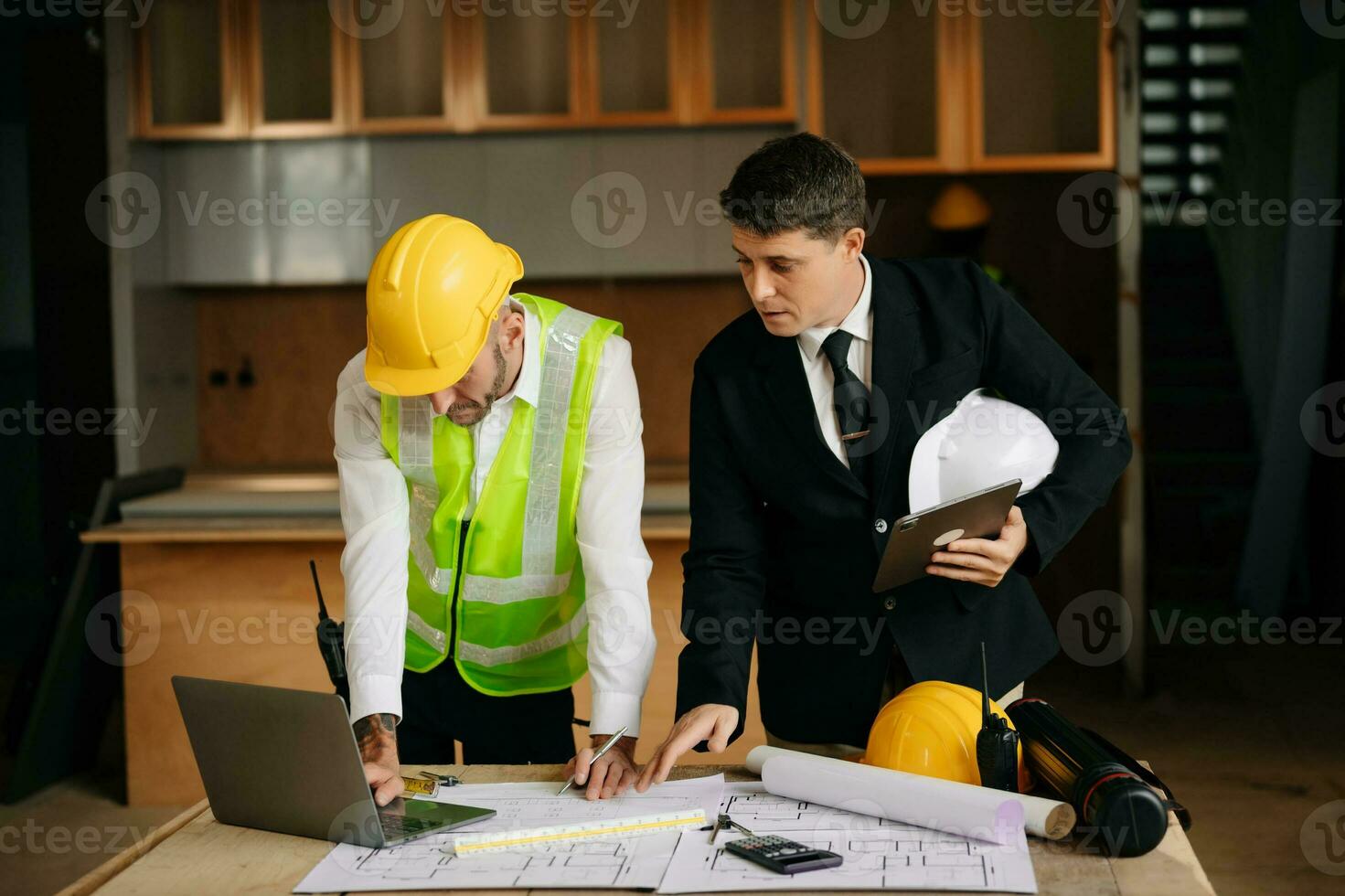 Engineers are discussing data working and laptop or tablet with architectural project at new construction site on big project. interior photo