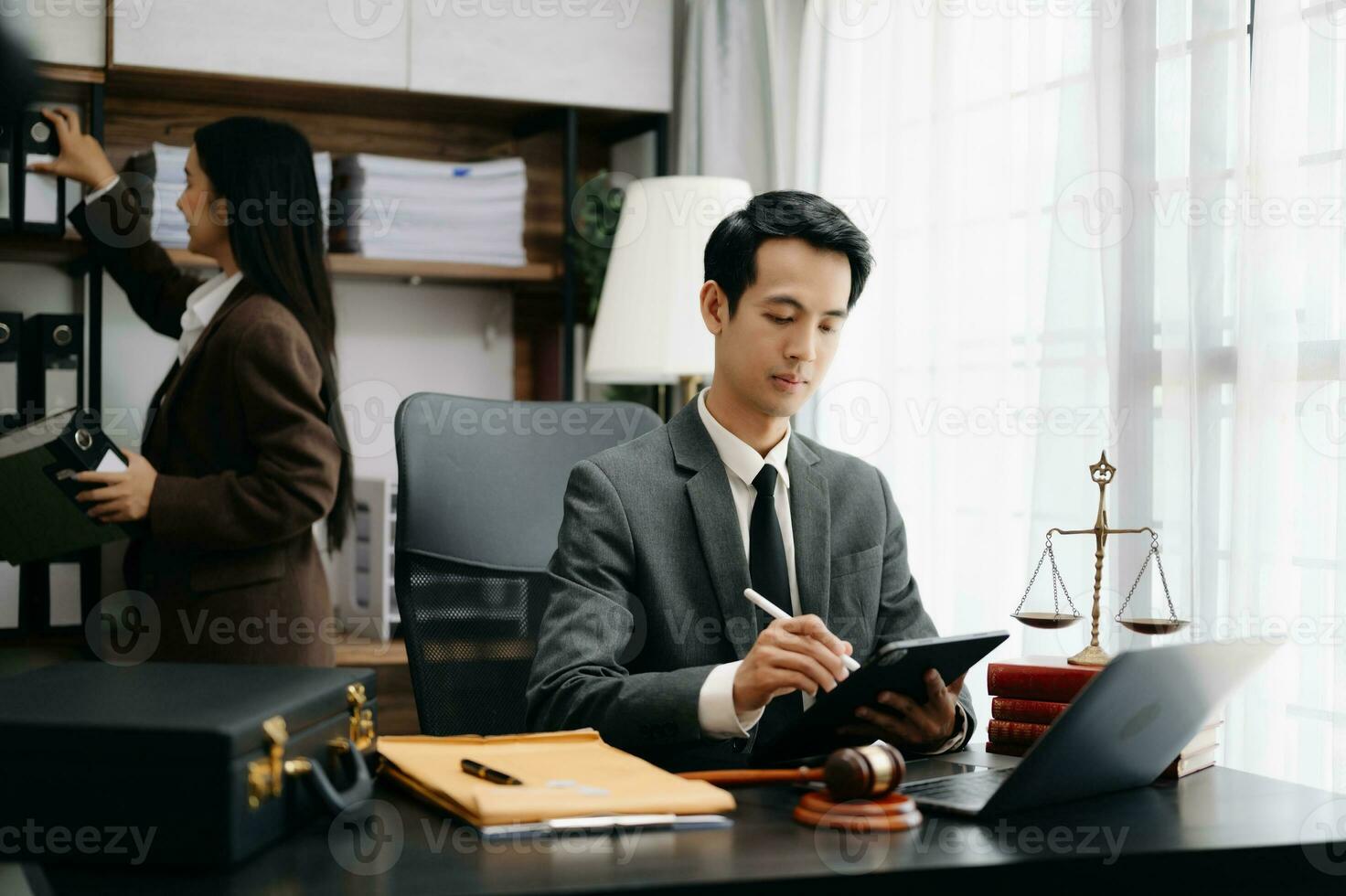Asian lawyer man working with a laptop and tablet in a law office. Legal and legal service concept. Looking at camera in modern office photo