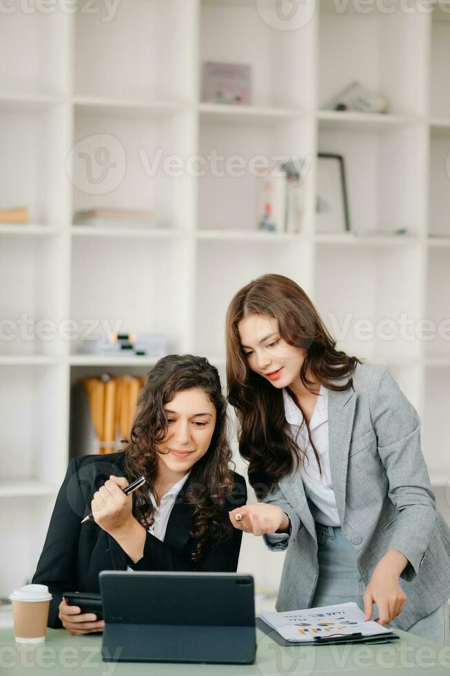 Businesswoman leading team meeting and using tablet and laptop computer with financial in coworking office photo