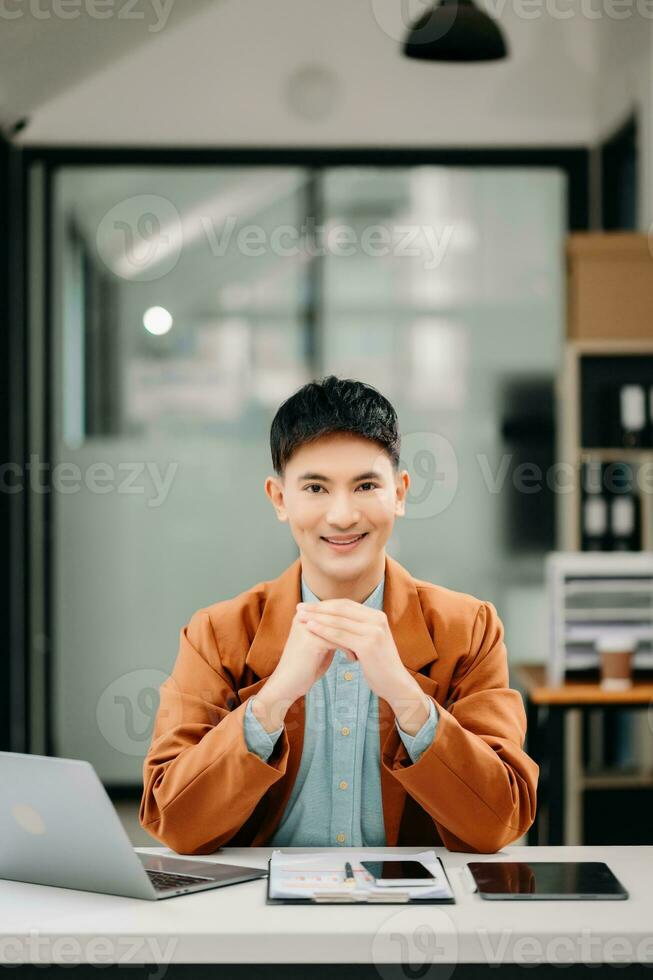 Young attractive Asian male office worker business suits smiling at camera in office photo