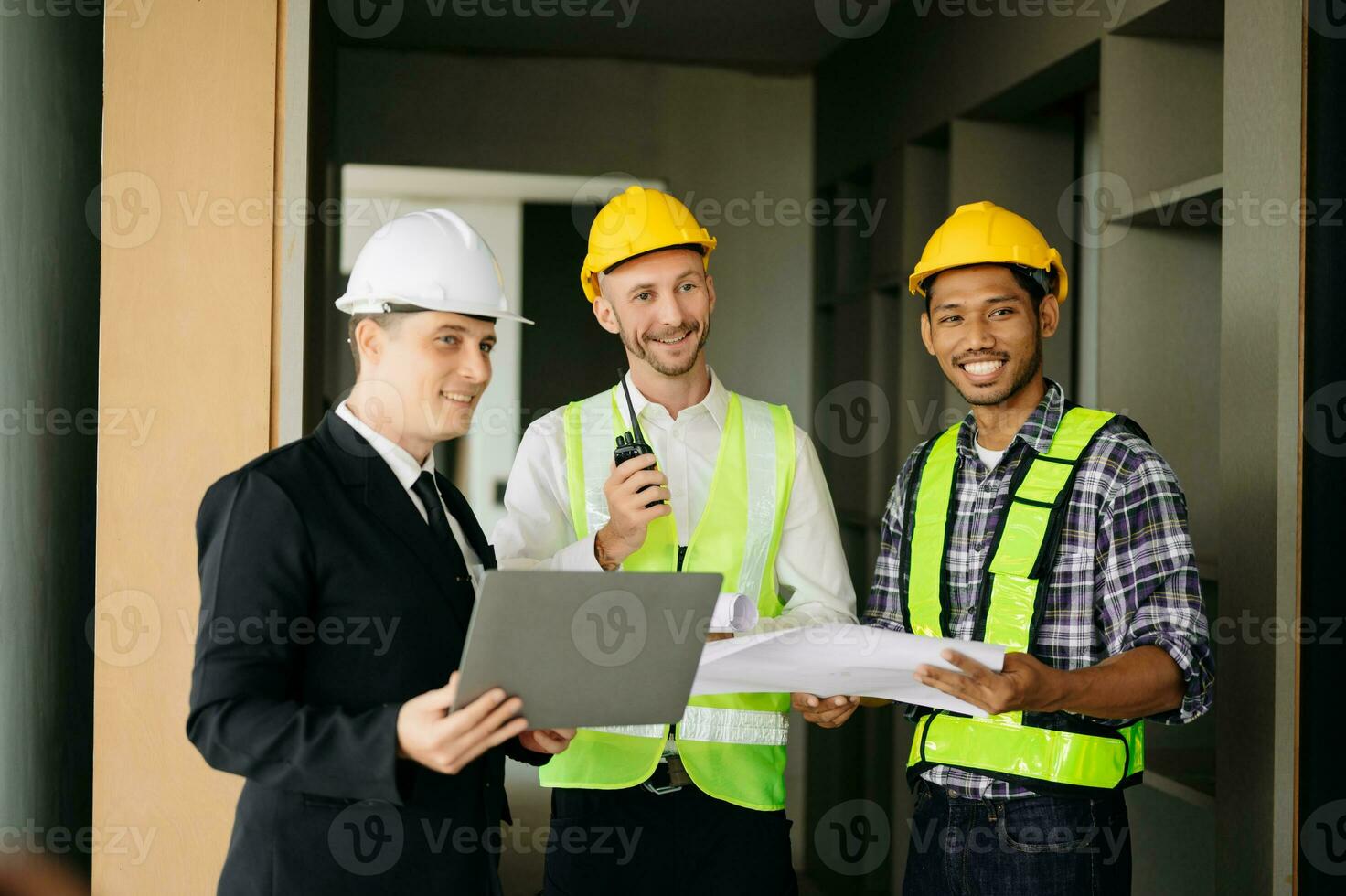 Architect caucasian man working with colleagues mixed race in the construction site. Architecture engineering on big project. Building in construction process interior. look at camera photo