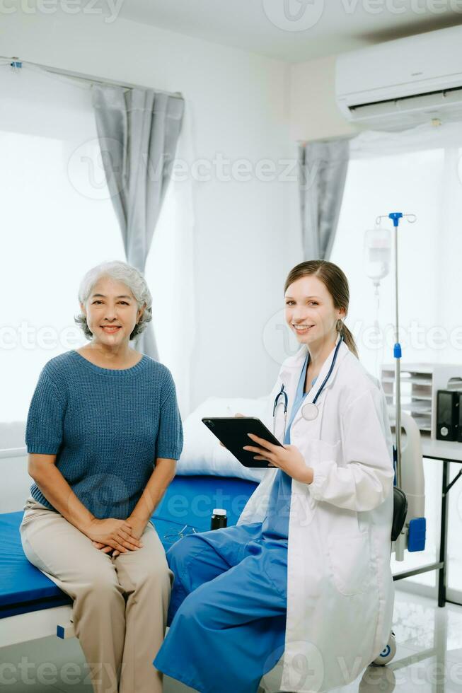 simpático hembra cabeza enfermero haciendo rondas lo hace chequeo en paciente descansando en cama. ella cheques tableta mientras hombre completamente recuperación después exitoso cirugía en hospital foto