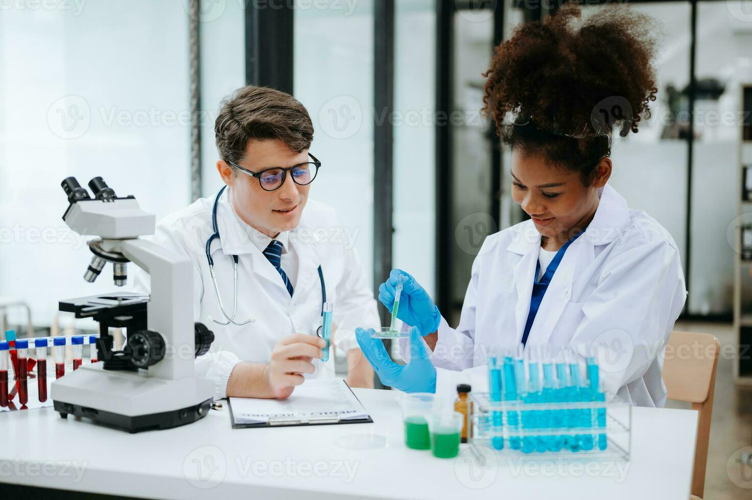 Focused mature male doctor and African female nurse look at tablet and laptop screen discuss anamnesis together. Concentrated diverse medical professionals photo