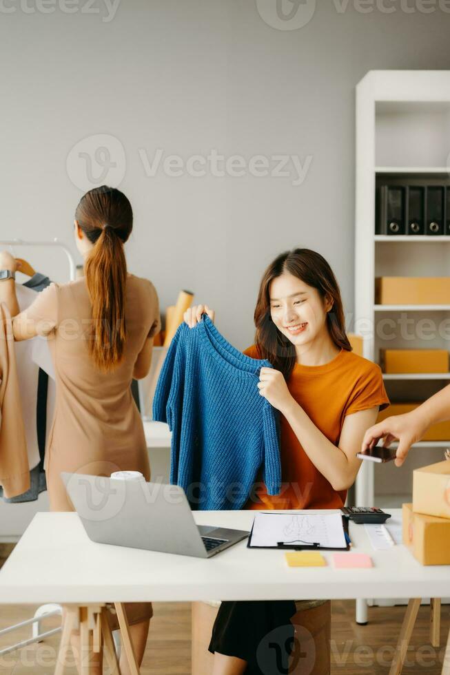 Young Asian business owner woman prepare parcel box and standing check online orders for deliver to customer on tablet, laptop Shopping Online concept. photo