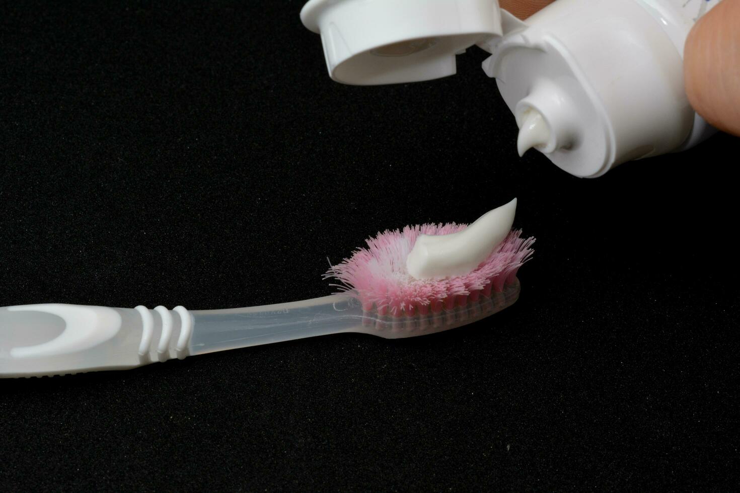 blanco pasta dental en un cepillo de dientes. negro antecedentes foto