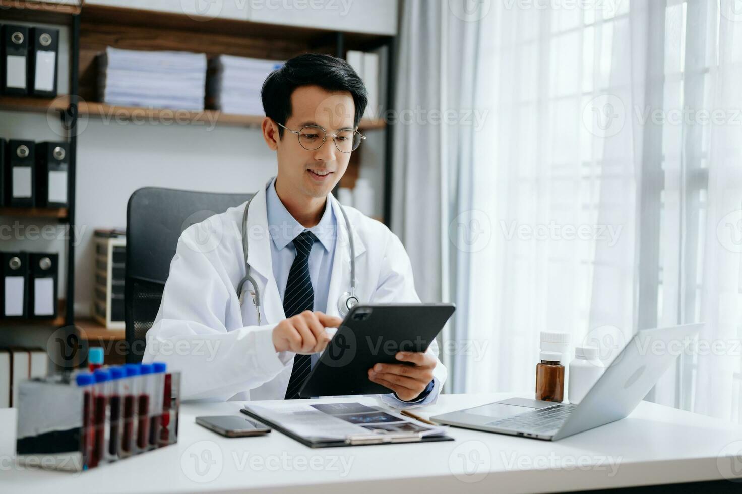 Medical technology concept. Asian Doctor working with mobile phone and stethoscope in modern office photo