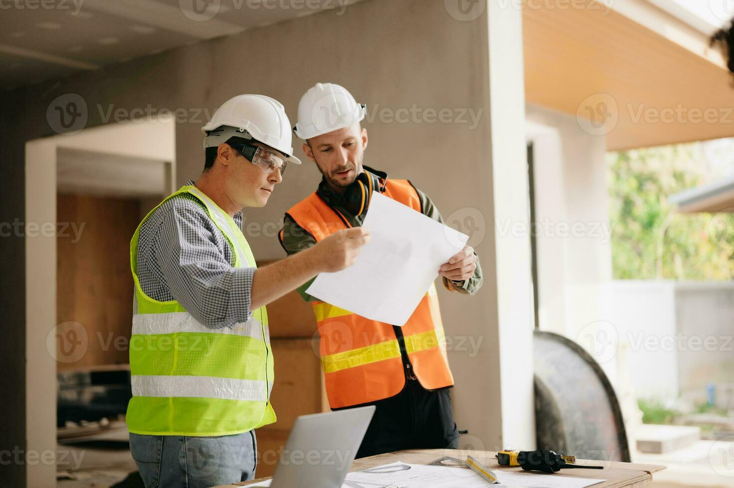 Contractor and architect looking at plan, tablet, laptop and talking about working on big project. Building in construction process interior. team work photo