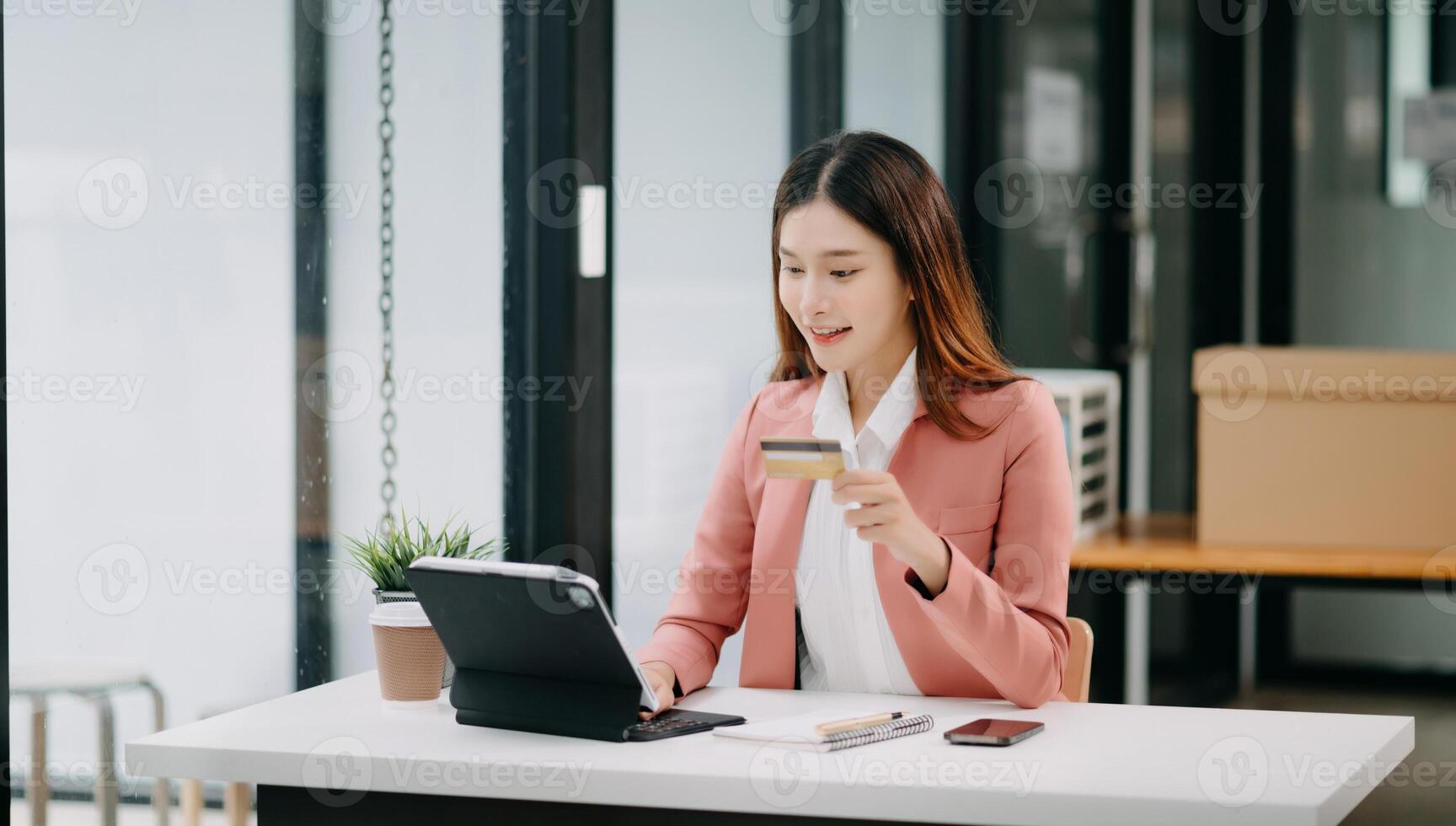 Asian Woman using smart phone for mobile payments online shopping,omni channel,sitting on table,virtual icons graphics interface screen photo