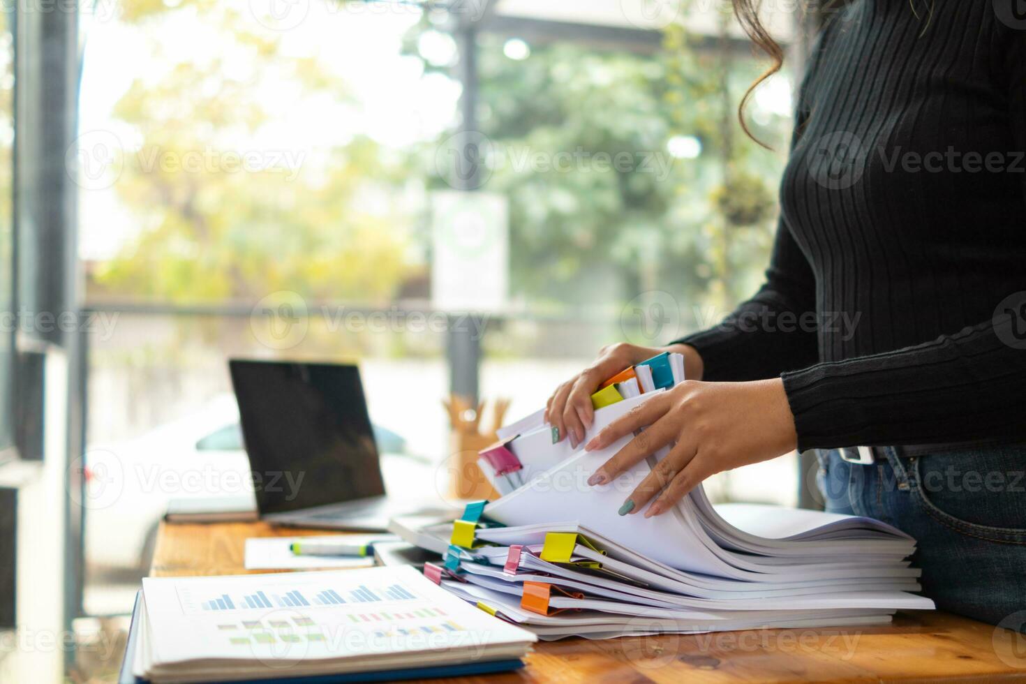 secretary searches through stacked documents on desk in office to find lease within stacked documents just before meeting. concept difficulty in finding hire purchase contract from stacked documents photo