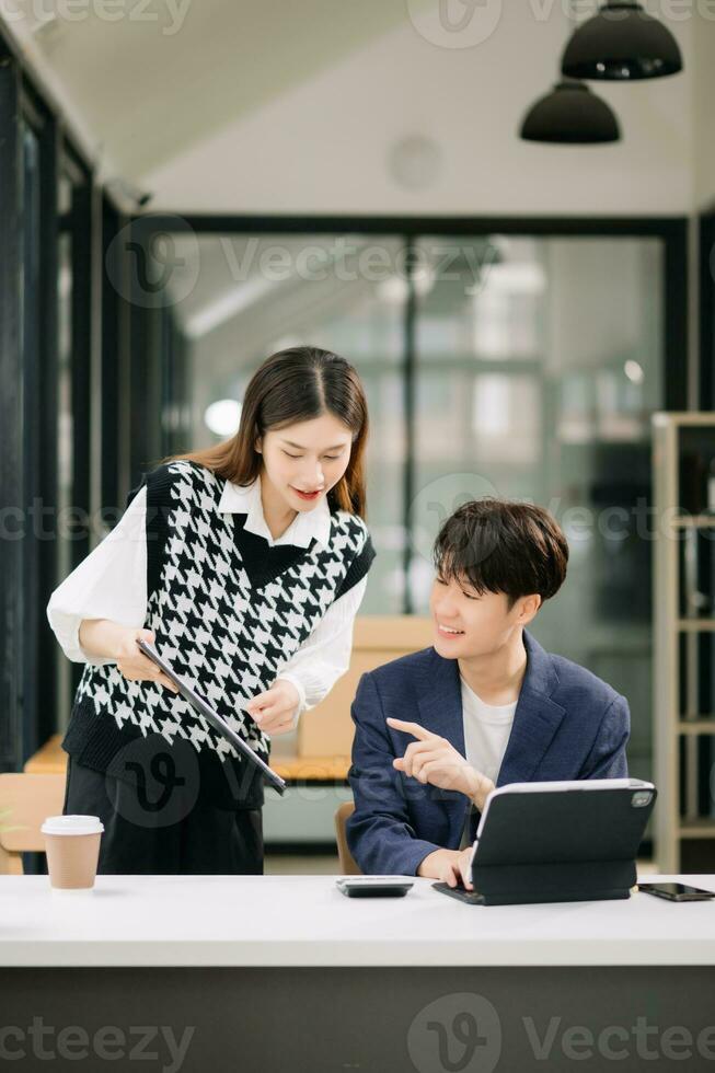 Two Asian business workers talking on the smartphone and using laptop at the modern office. photo