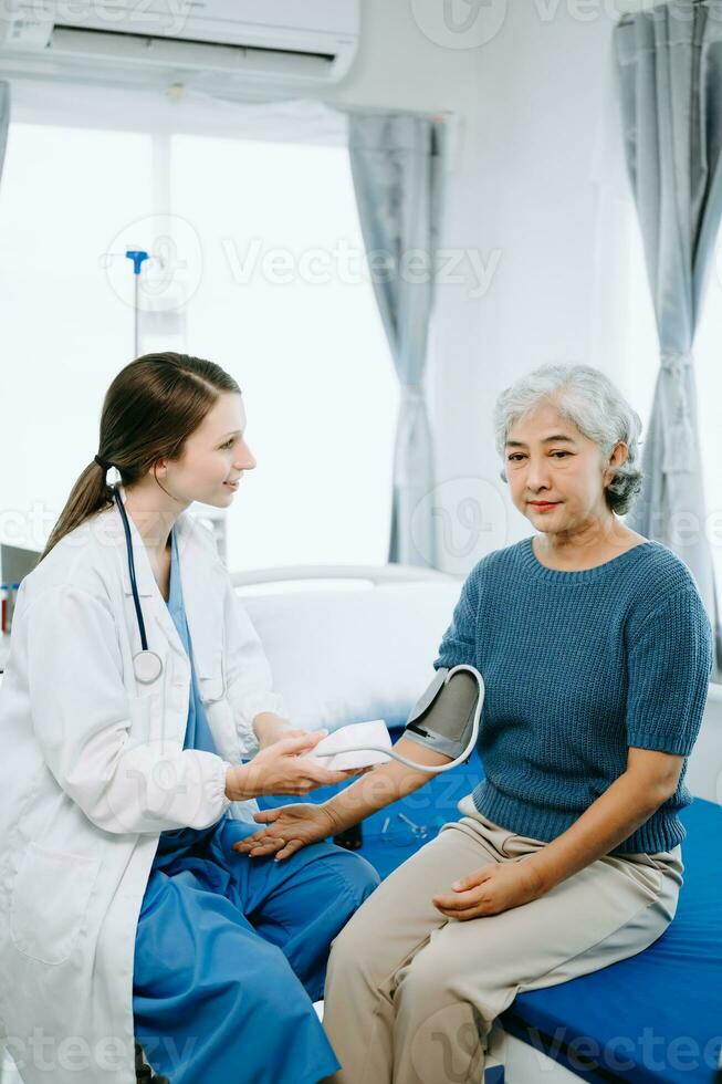 Caucasian doctor smiling take care of a senior patient in hospital. Friendly nurse or therapeutic treat client Professional medical service concept. photo