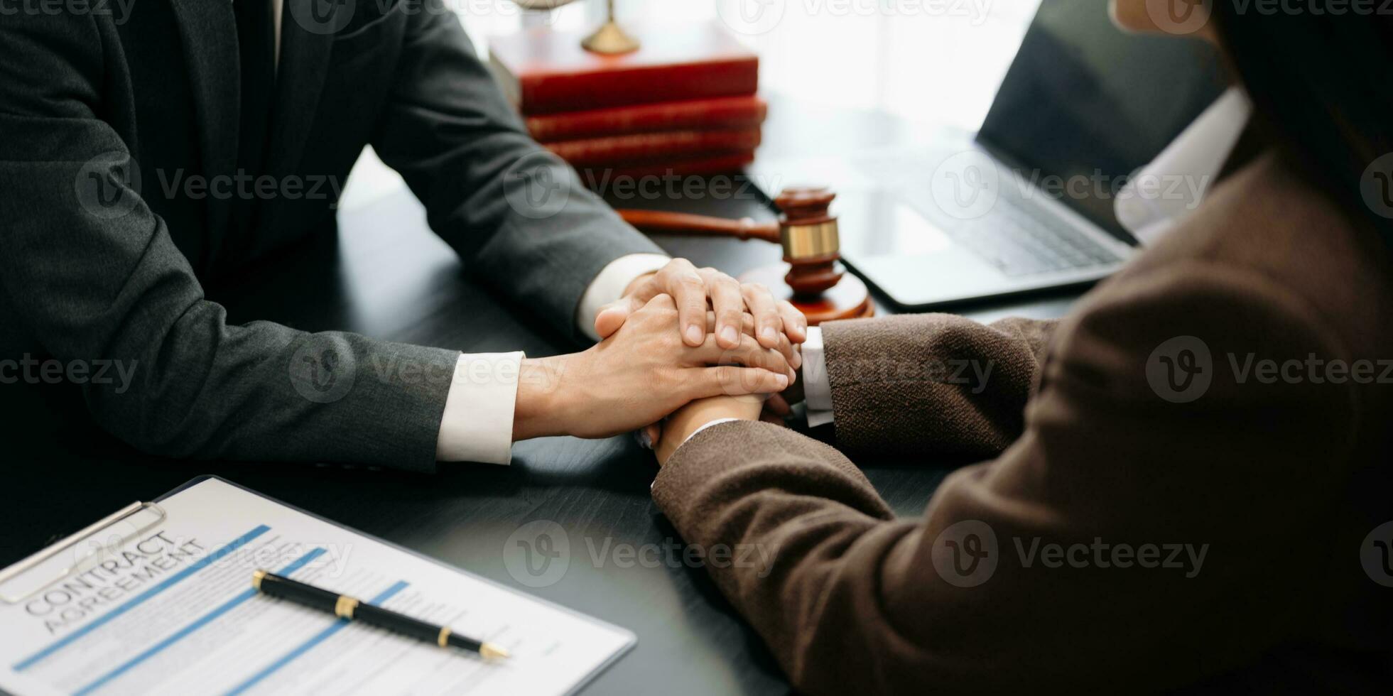 Business people compassionately holding hands and discussing contract papers with laptop and tabletat office photo